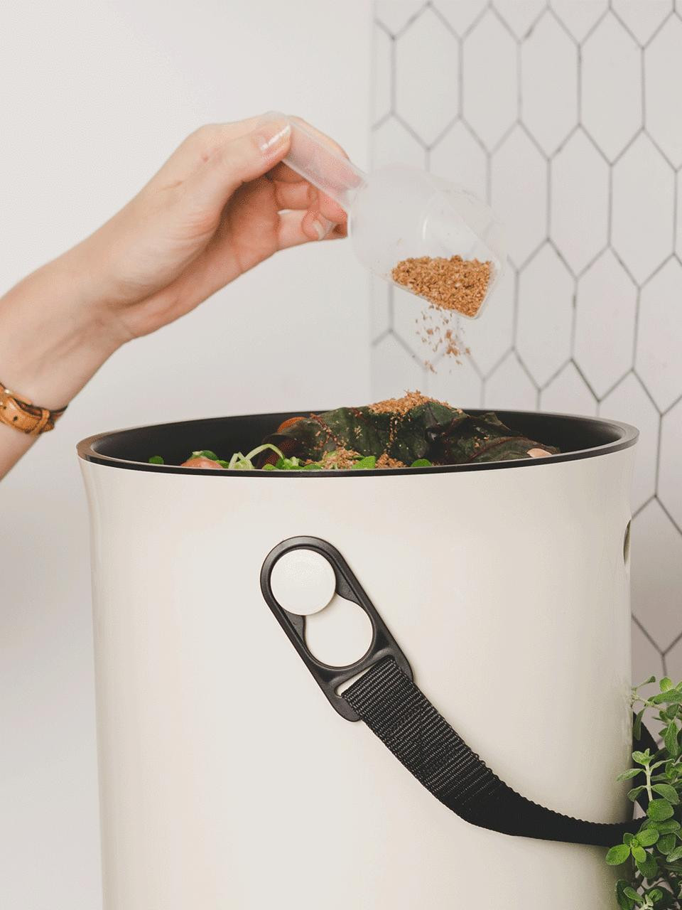 Volle bokashi emmer waarover microben worden gestrooid.